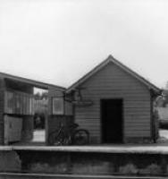 033 Parcels Shed.
Note the construction of the ‘up’ main platform behind the broken wall.
Note the clear open field in the distance with village in background.
